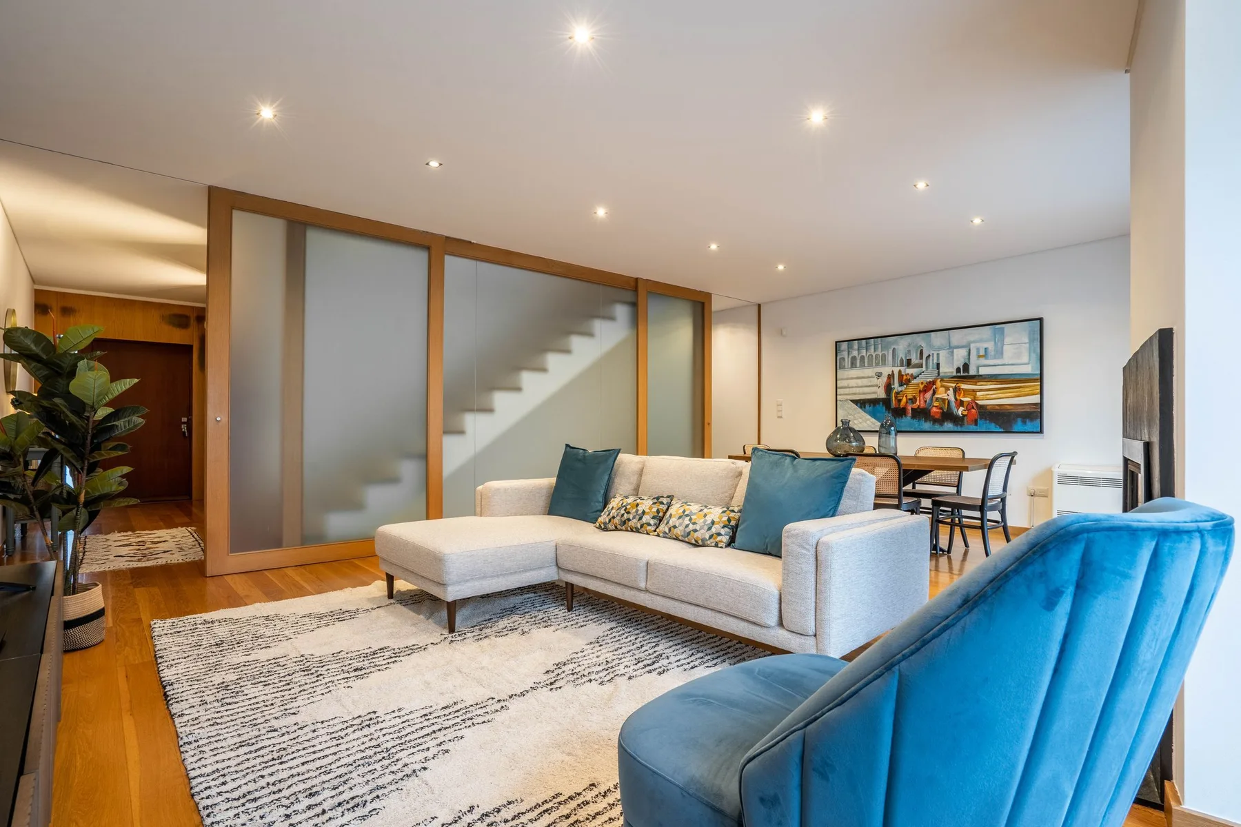 A bright living room with a sectional sofa, blue seating, and a dining area.