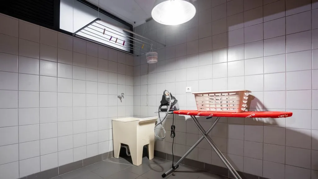 A tiled laundry room with an ironing board and an iron.
