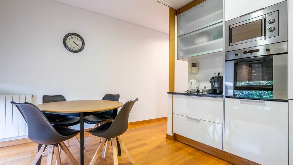 A dining area with a table and seating beside a built-in kitchen.