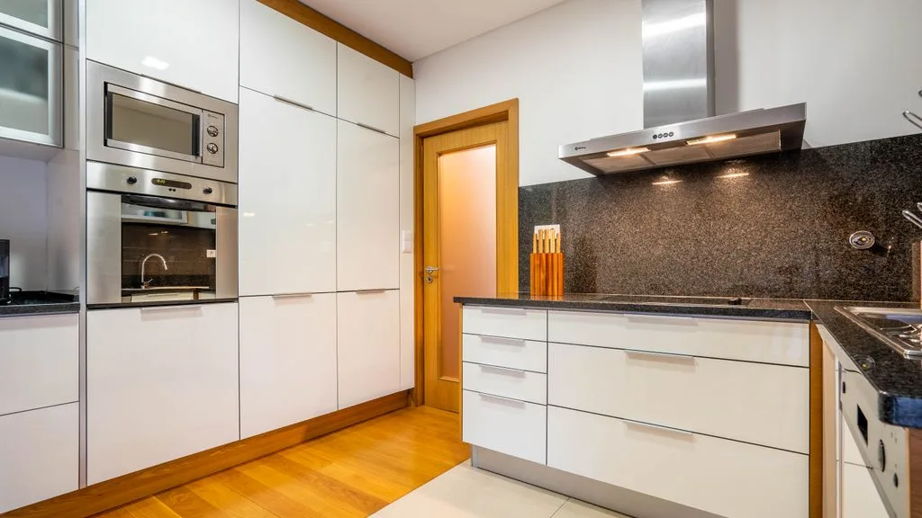 A modern kitchen with white cabinets and built-in appliances.