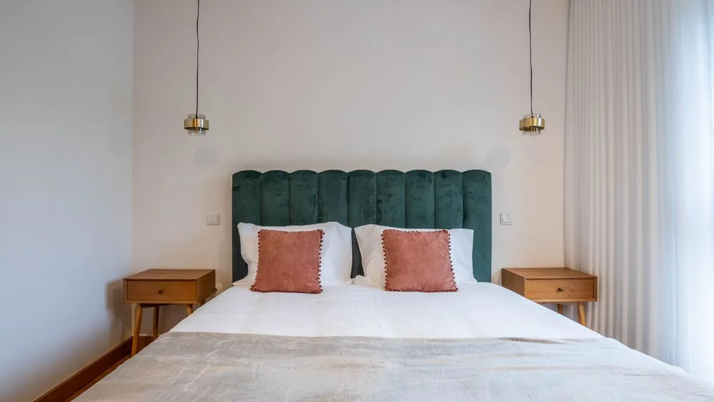 A bedroom with a bed, green headboard, and matching bedside tables.