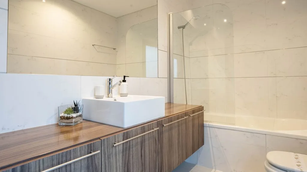 Un baño moderno con lavabo sobre encimera y ducha de cristal.