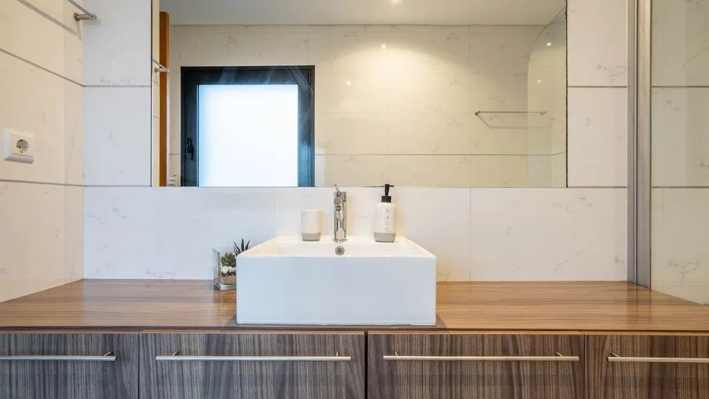 A modern bathroom vanity with a wide mirror and a vessel sink.