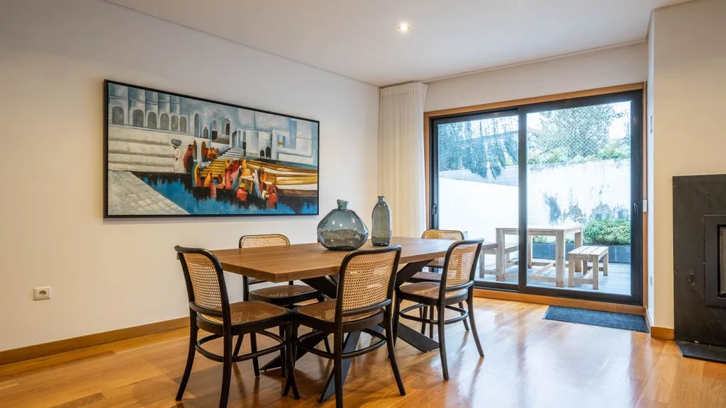 Dining area with a wooden table and chairs beside a large window.
