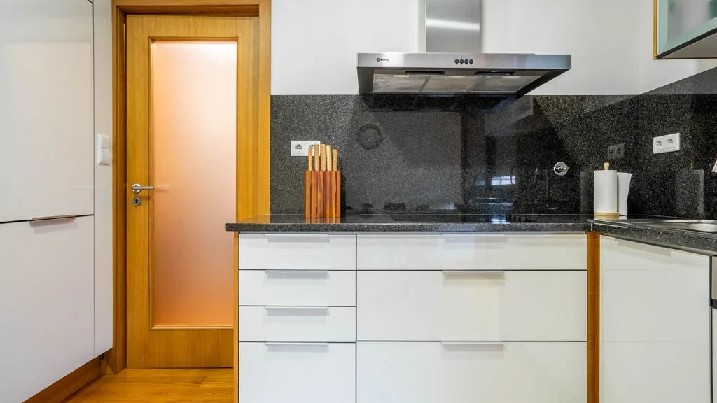 A modern kitchen with white cabinets and a dark countertop.