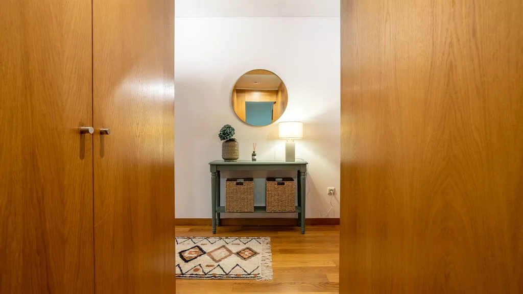 A hallway with wooden doors and a console table beneath a round mirror.