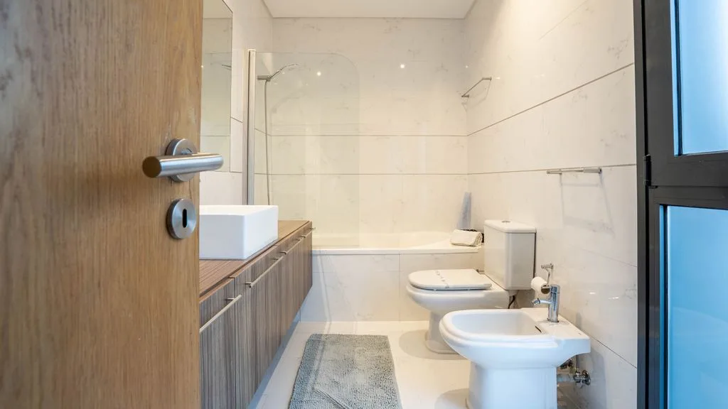 A bright bathroom with a bathtub, toilet, and bidet.
