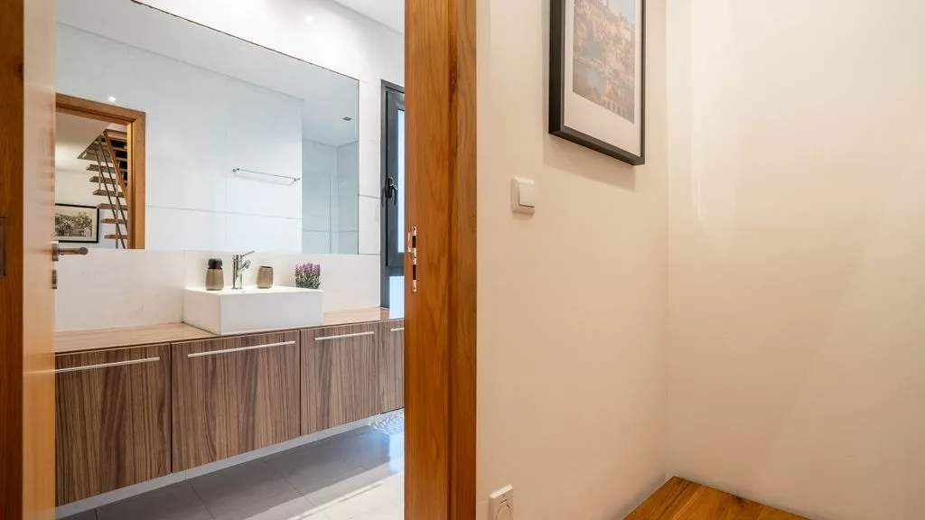 A bathroom vanity with a wide mirror and wood-finish cabinetry.
