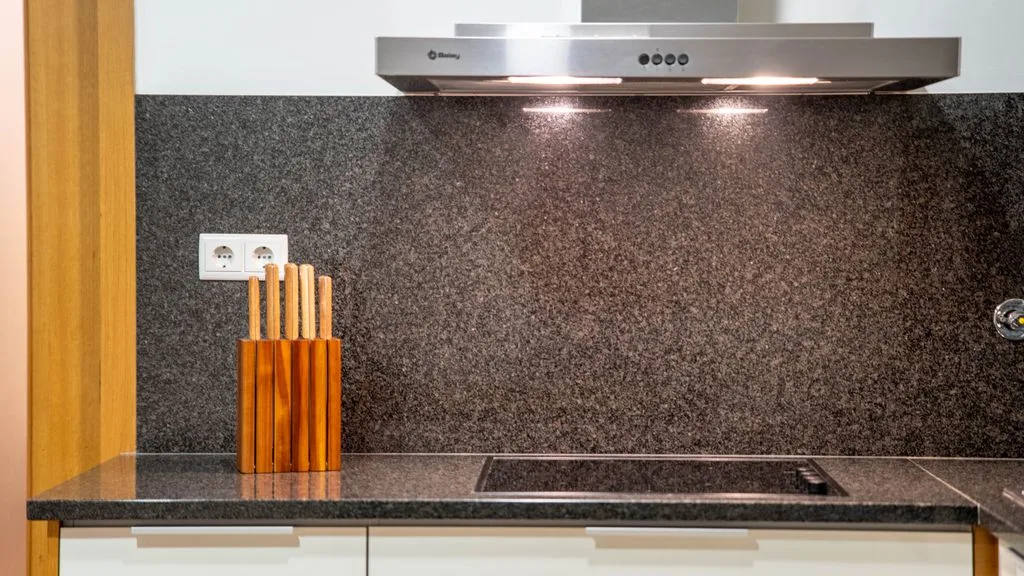 A kitchen counter with a knife block beneath a range hood.