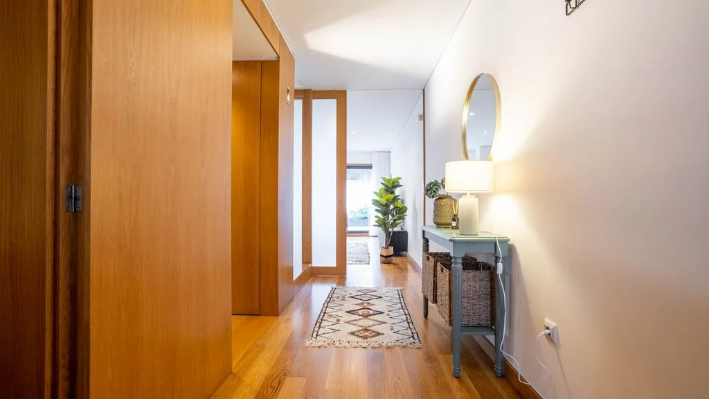 A bright hallway with wooden doors, a patterned runner, and a console table.