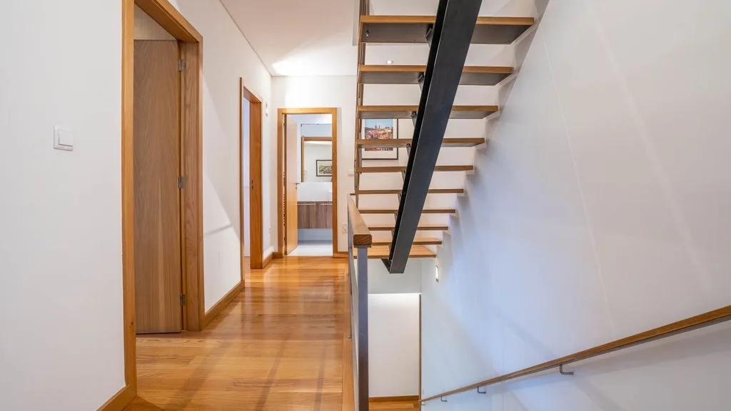 A bright interior hallway beside an open staircase with wooden steps.