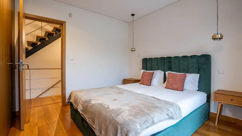A bedroom with a bed and a dark green upholstered headboard.