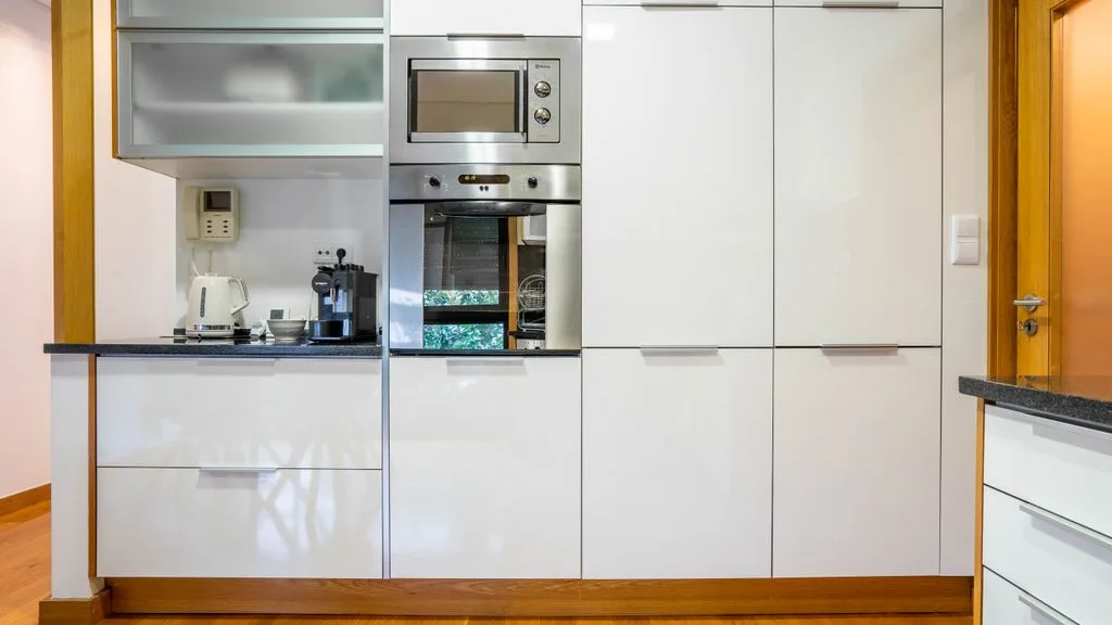A modern kitchen with white cabinetry and built-in appliances.