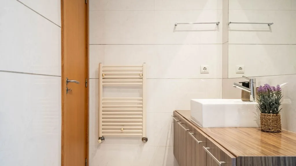 A bathroom with a wood countertop vanity and a wall-mounted towel warmer.