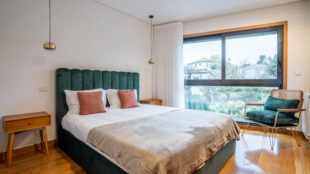 Un dormitorio con una cama, una mesita de noche y una ventana grande.