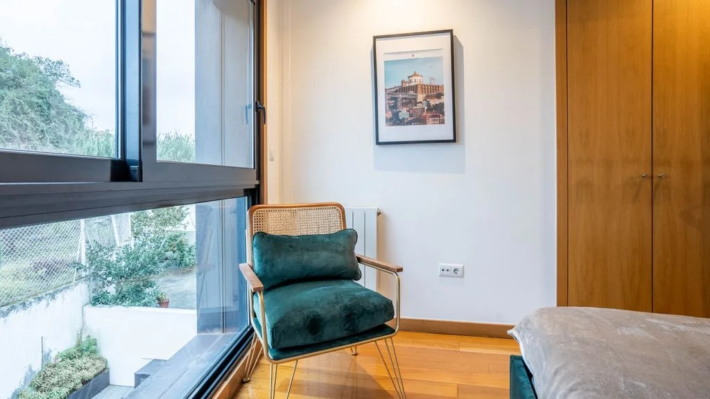A bedroom with a green armchair beside a large window.