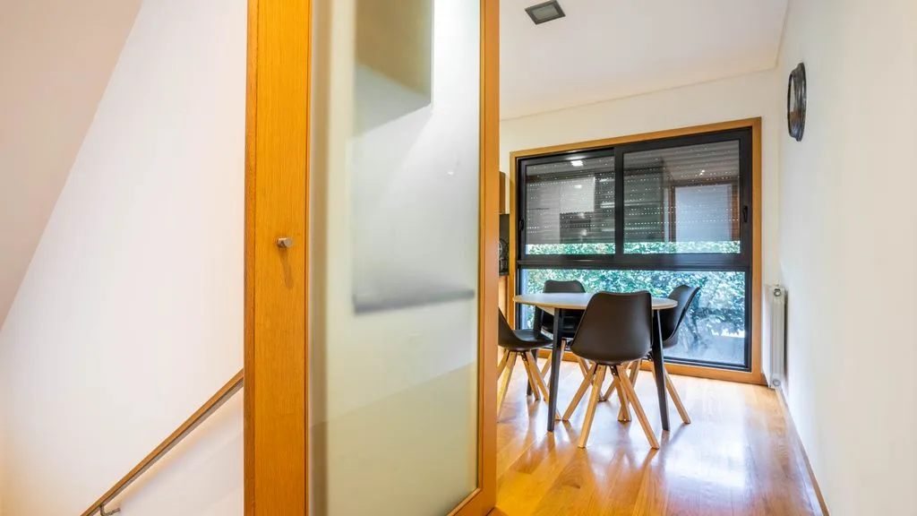 A dining area with a table and chairs beside a large window.
