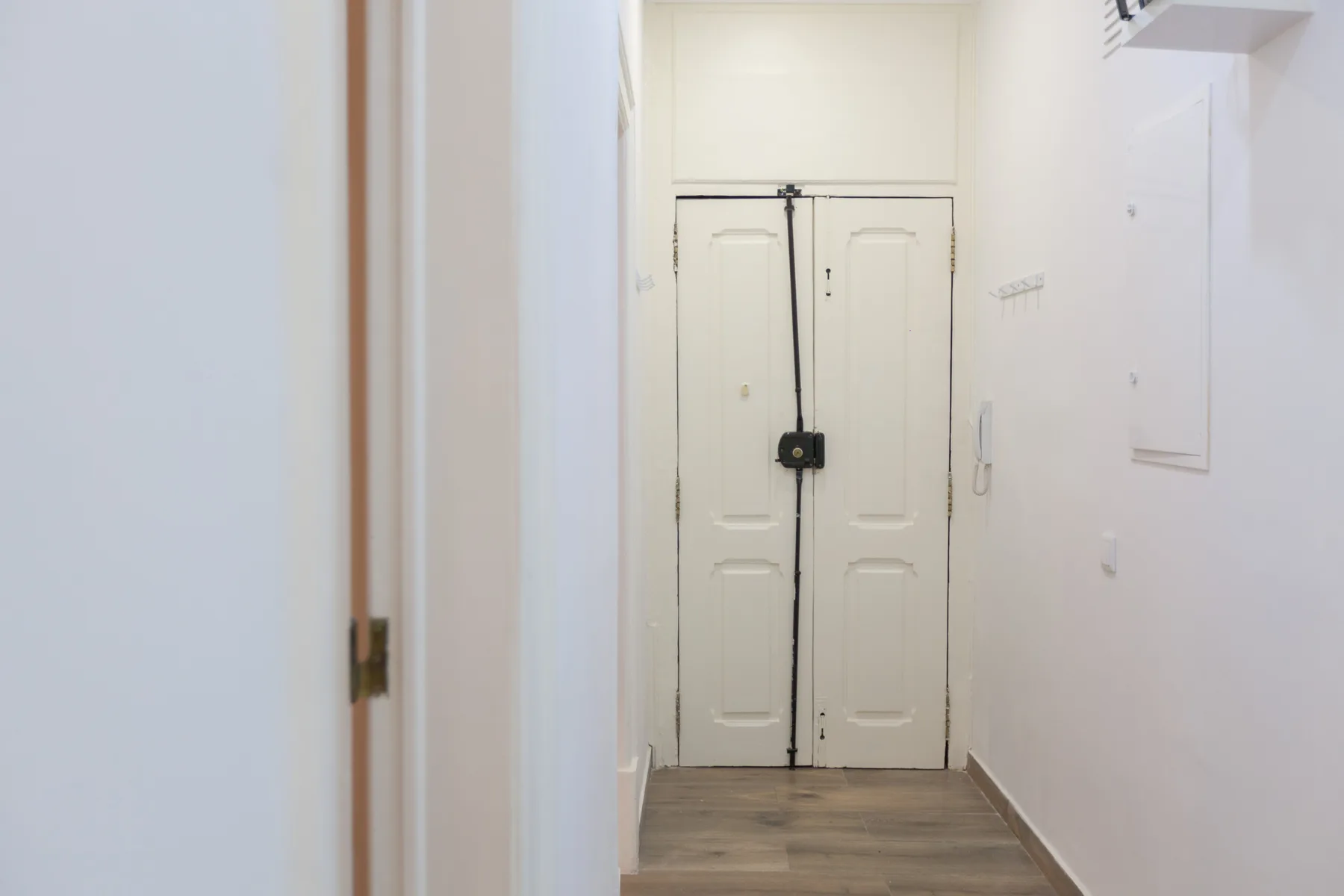 A narrow hallway leads to a pair of white doors.