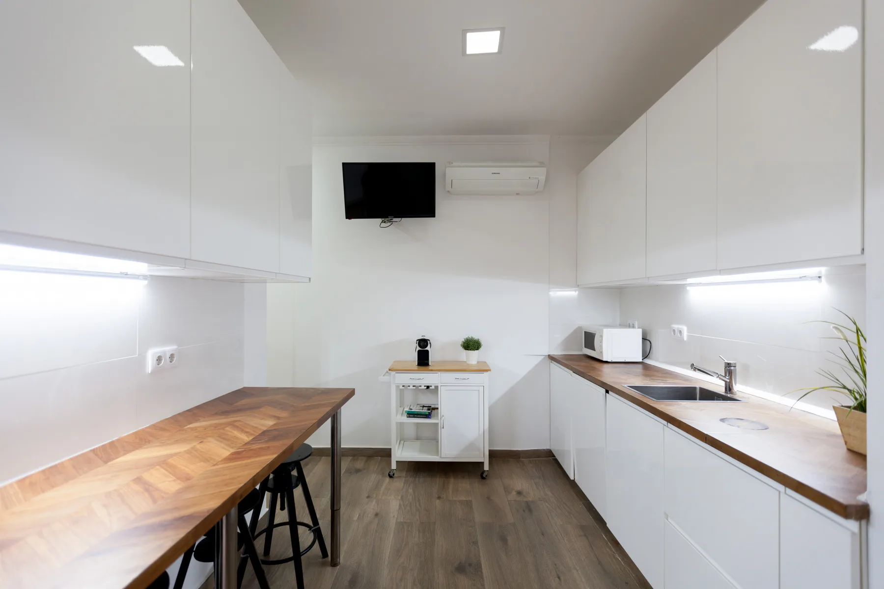 A bright kitchen with white cabinetry and wooden countertops.