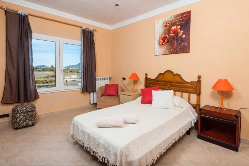 A bedroom with a wooden bed, white bedding, and a window with dark curtains.