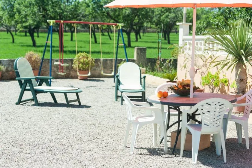 An outdoor patio has seating and a table beneath an orange umbrella.