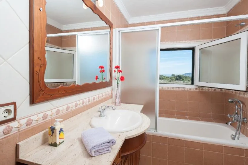 A bathroom with a bathtub, vanity, and window overlooking the landscape.