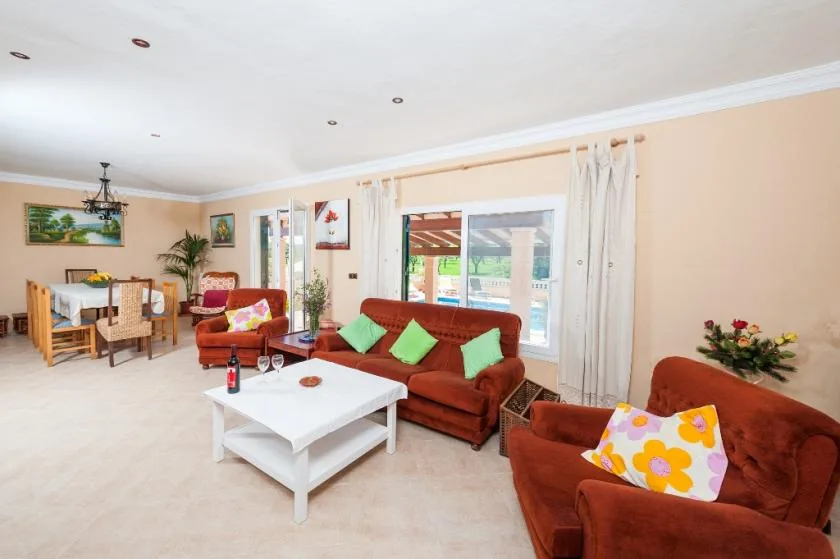 A living room with seating around a white coffee table and a dining area.