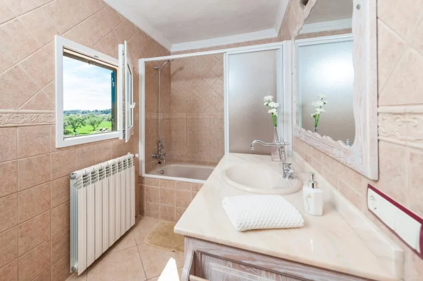 A tiled bathroom with a sink, mirror, and frosted-glass shower.