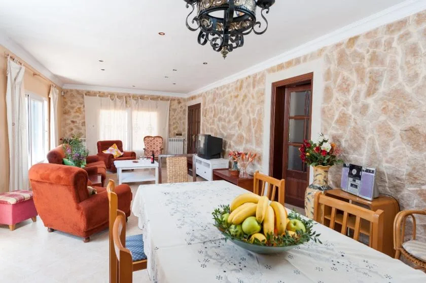 A dining and living room with a long table, seating, and a television.