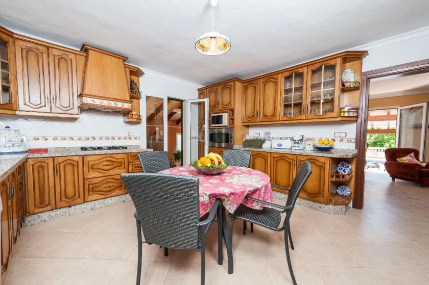 A kitchen with wooden cabinets and a dining table covered with a red cloth.
