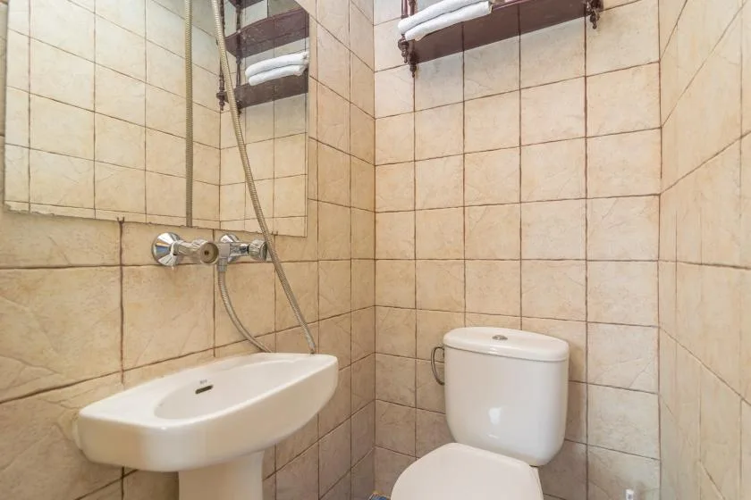 A tiled bathroom with a wall-mounted sink and shower fixtures.