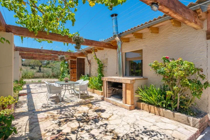 An outdoor dining patio with a table, seating, and a built-in grill.