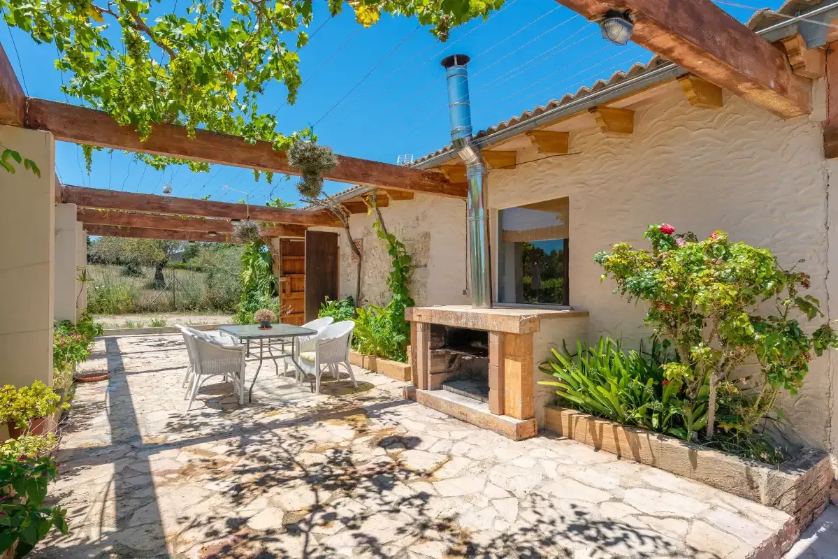 A stone-paved outdoor patio with a dining table and built-in barbecue.
