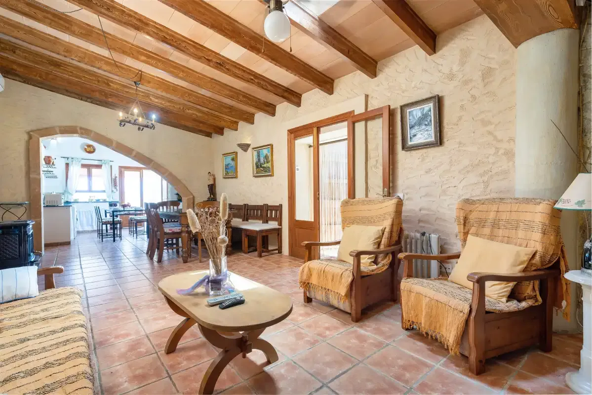 A rustic living and dining area with seating and exposed wooden ceiling beams.