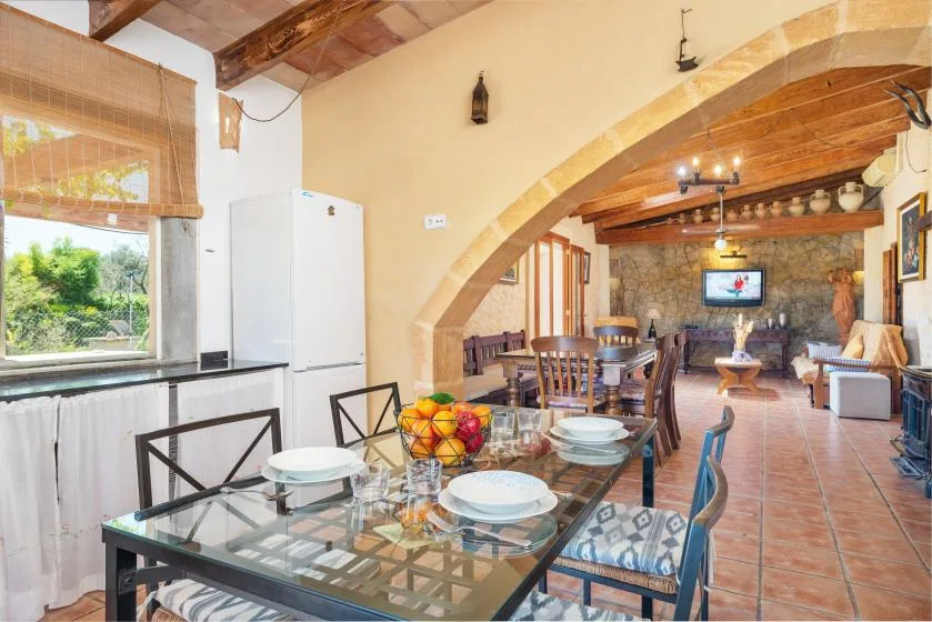 A dining area with a glass table and wooden seating beneath a stone arch.