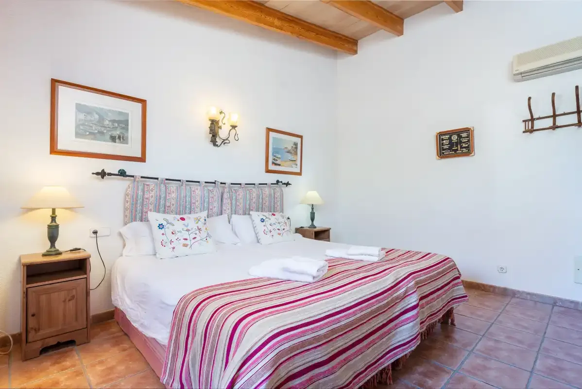 A bedroom with a bed dressed in striped bedding and bedside tables.