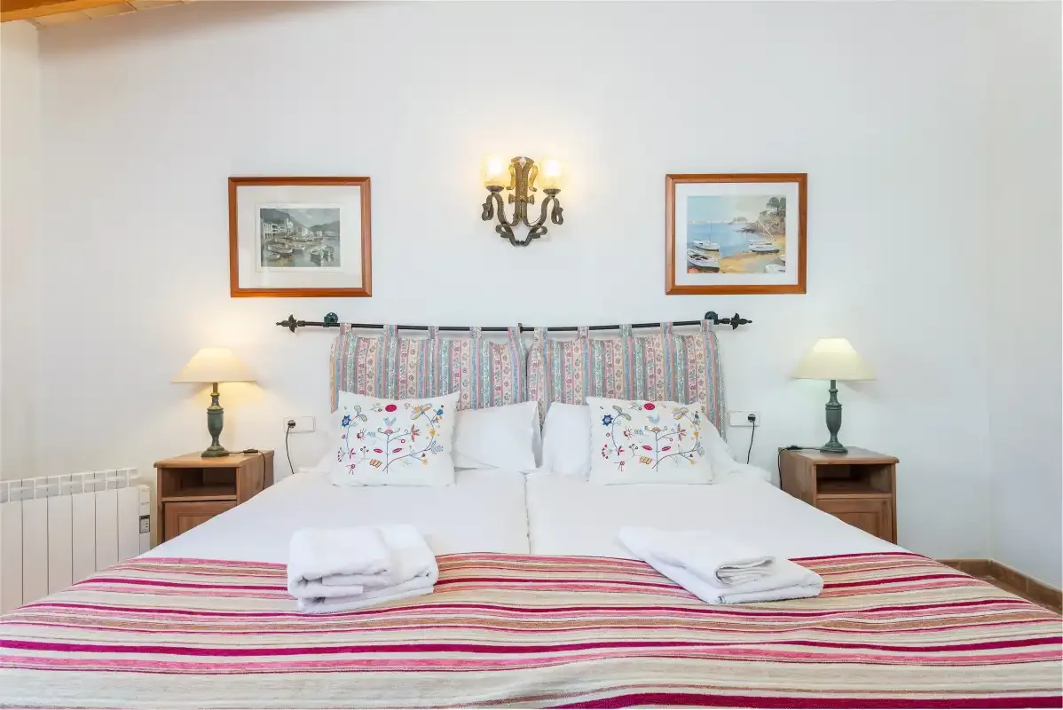 A bedroom with a neatly made bed and framed pictures above it.