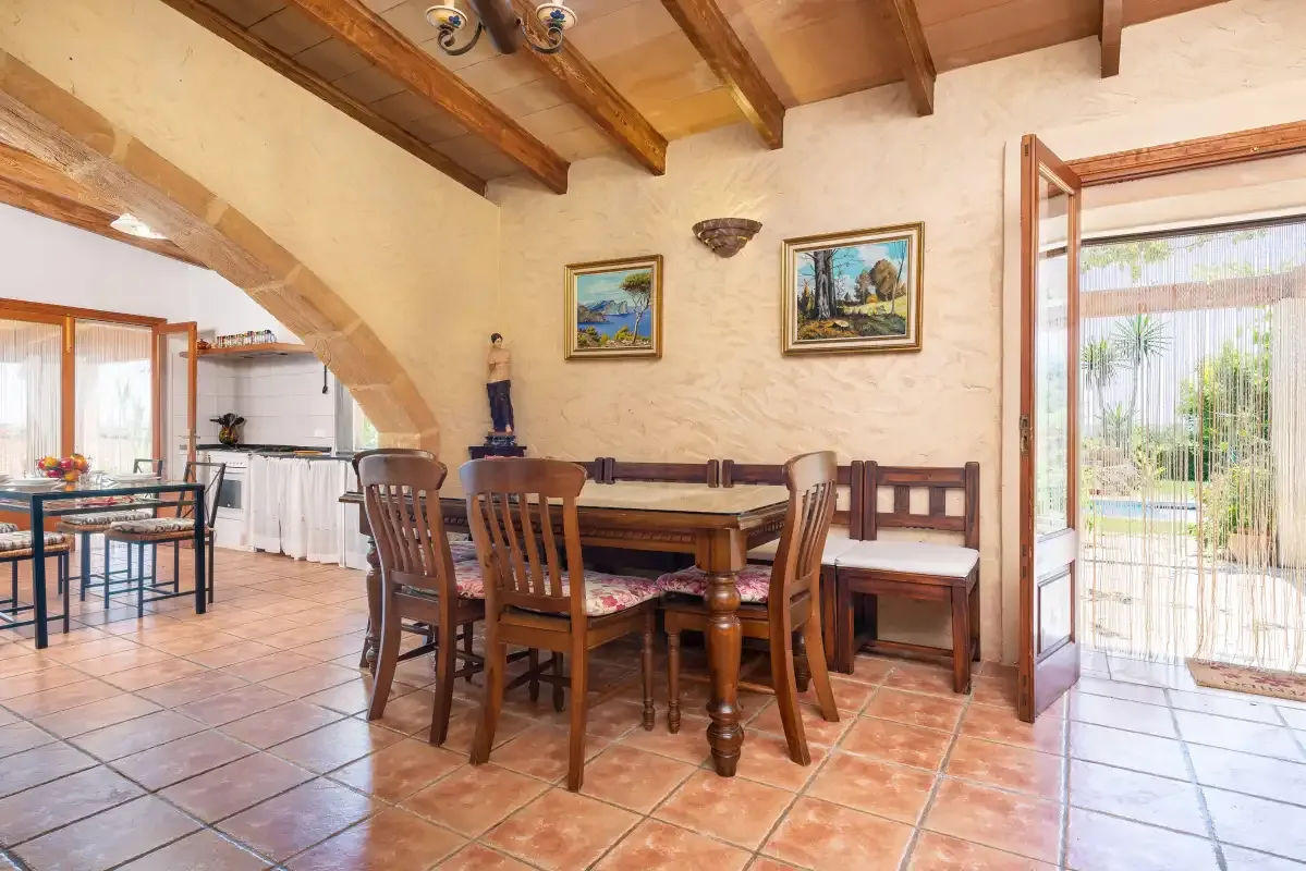 A dining area with a wooden table and seating beneath exposed ceiling beams.