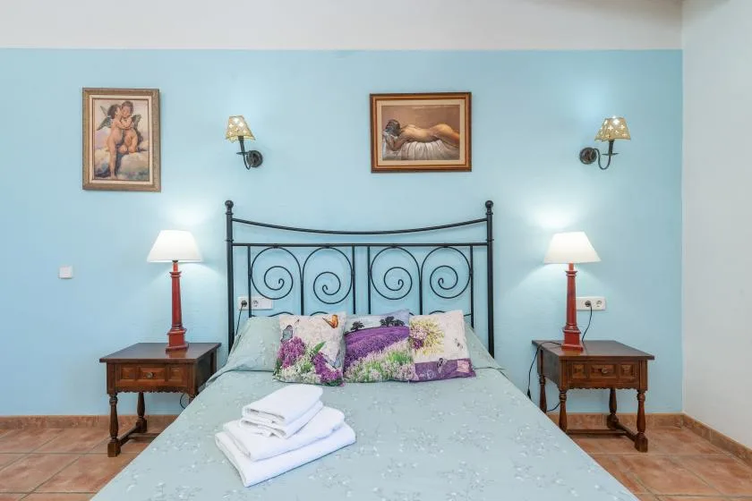 A bedroom with a metal bed, floral pillows, and matching bedside tables.
