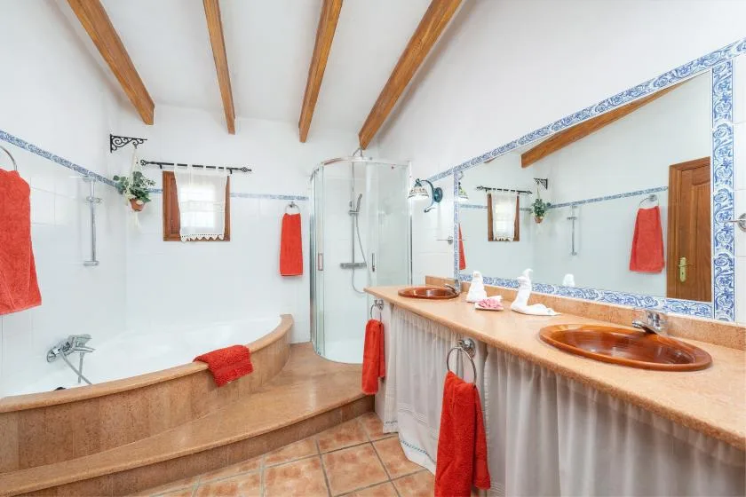 A tiled bathroom with a bathtub, glass shower, and long sink counter.