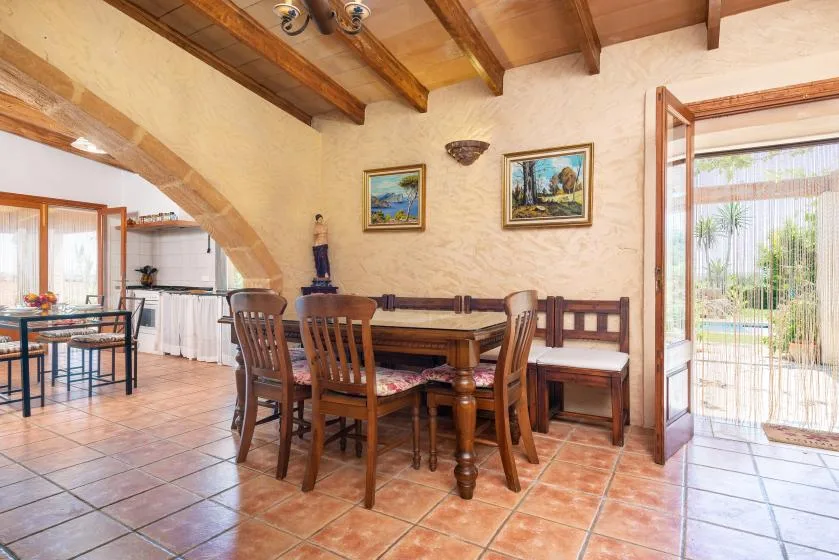 A dining area with a wooden table and chairs beside an open patio door.