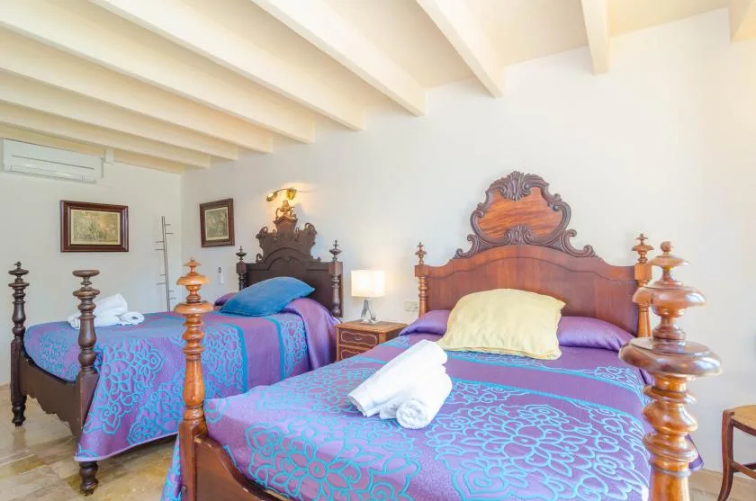 A bedroom with two beds dressed in purple and blue patterned bedding.