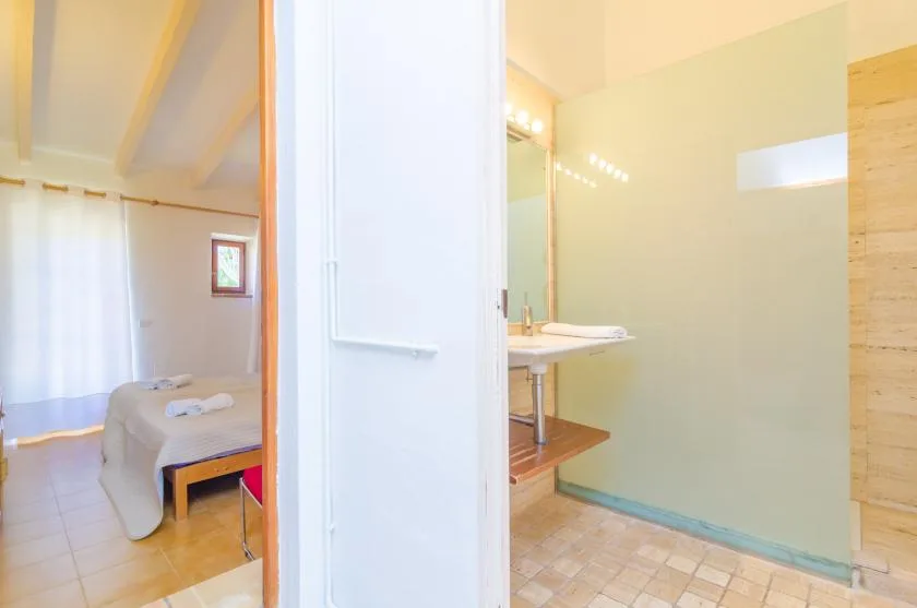 A bedroom and adjoining bathroom are visible, with a bed beside a sink.