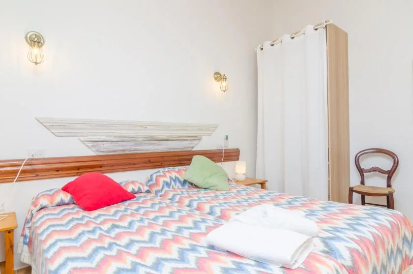 A bedroom with a bed covered in a colorful patterned bedspread.