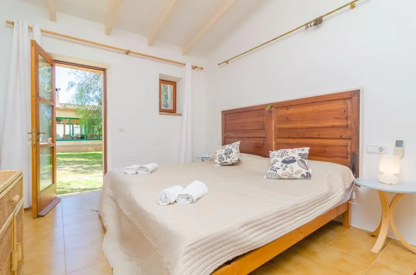 A bedroom with a large bed and an open glass door leading outside.