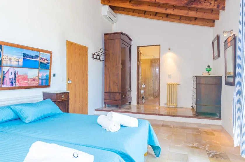 A bedroom with a turquoise bed, wooden wardrobe, and tiled floor.