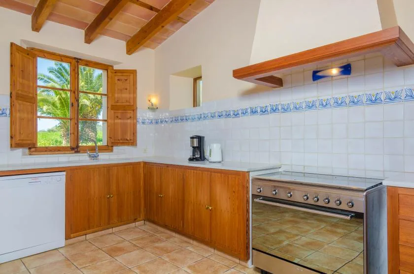 A kitchen with wooden cabinets, a large stove, and a window overlooking greenery.