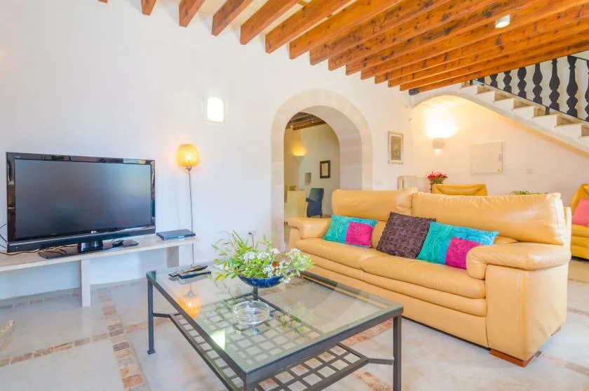 A bright living room with a beige sofa and glass coffee table.