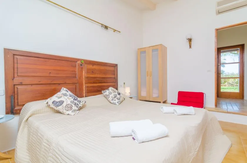 A bedroom with a double bed, patterned pillows, and a wooden headboard.