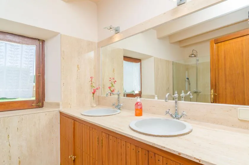 A bathroom vanity with two sinks sits beneath a large mirror.